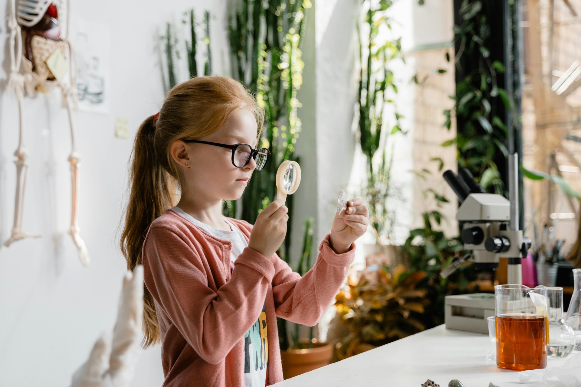 Image of science in action as young girl inspects microscope slide with magnifying glass